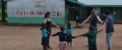 Local children play a game outdoors with a group of High School Special volunteers. Group of teenage volunteers in Ghana play a game outdoors with children at a rural school.